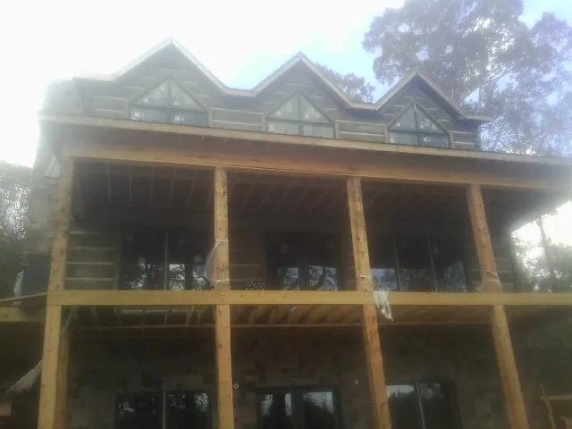 Dormers and porch framing on a large log home under construction — Roof Coating work by our crew in Rose Hill