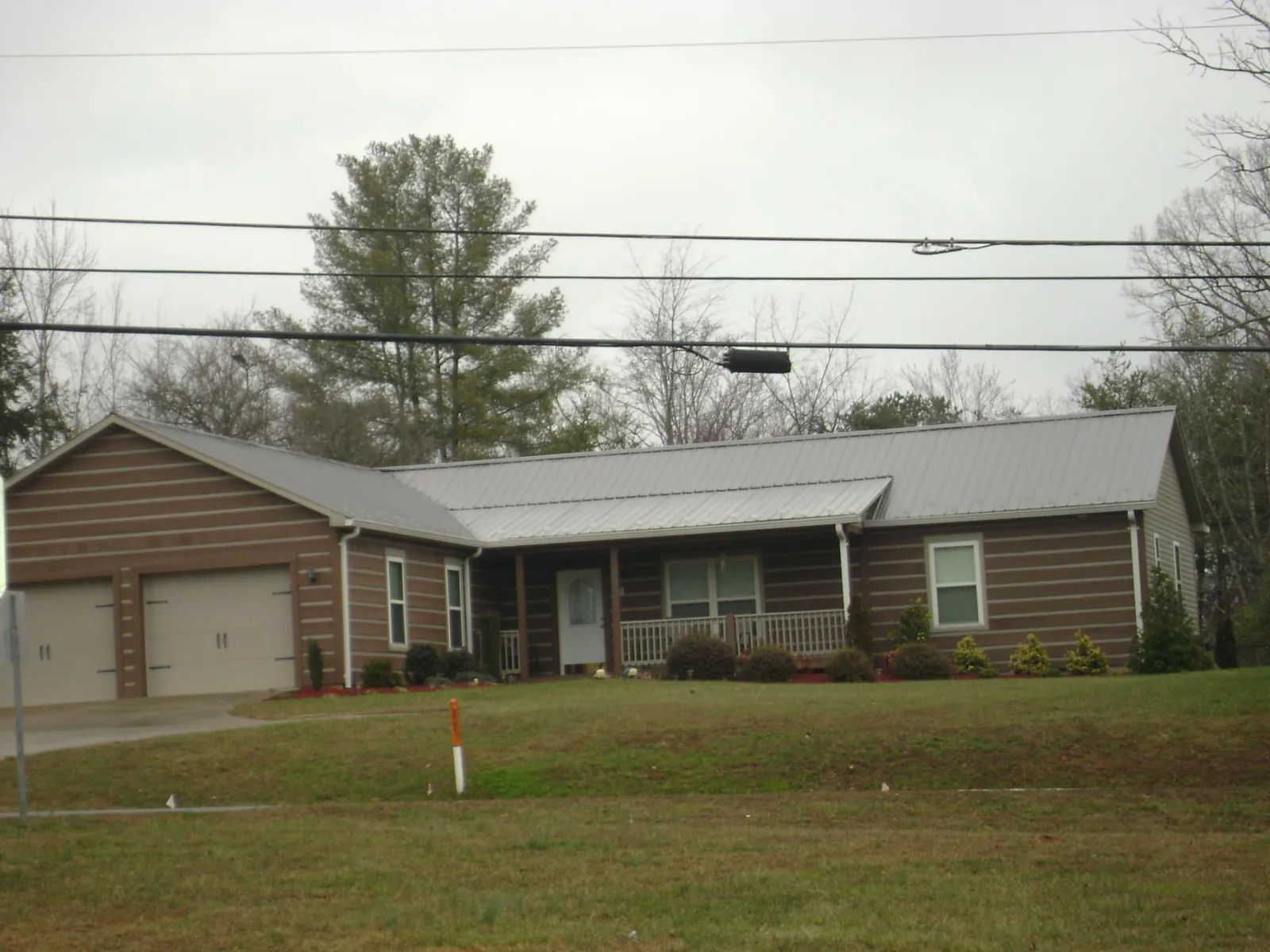 Gray metal roof on a log sided ranch home with a front porch in Rose Hill
